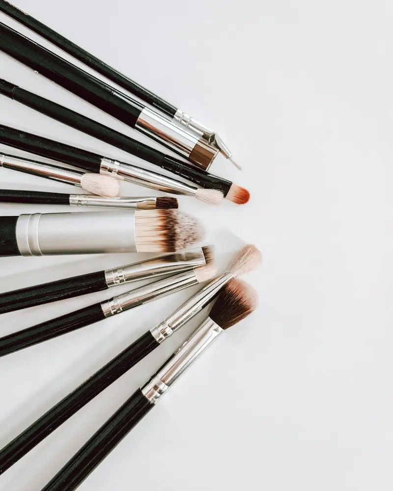 A fan of makeup brushes laid out on a white surface