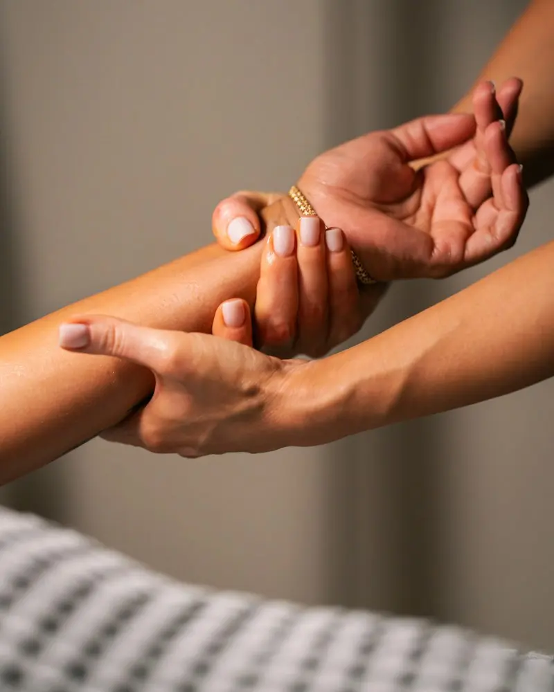A therapist’s hands massaging a client’s forearm